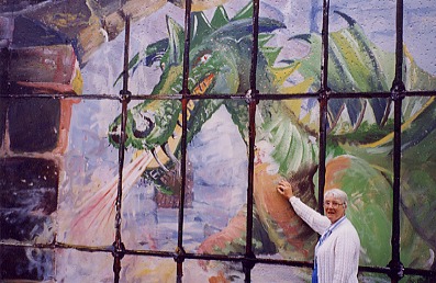 Angela standing beside large mural of dragon in cage