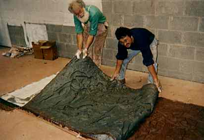two people remove rubber mold  from clay original